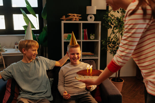 Children celebrating birthday with cake and party hats
