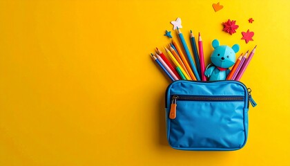 School essentials blue pencil case filled with vibrant pencils and a toy bear, adorned with felt shapes, against a sunny yellow backdrop