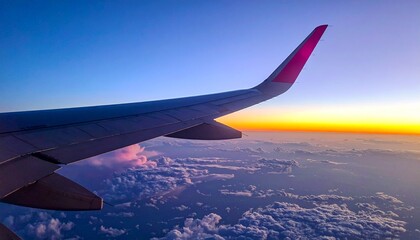 Airplane wing over clouds at sunset