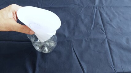 Hand holds funnel over bottle for clean, controlled liquid transfer. Ideal for kitchen or lab scenes focused on precision pouring and no-spill setups - Powered by Adobe