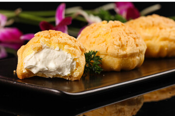 Cream puffs with white filling dessert showcase on elegant dark plate