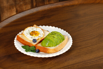 Avocado Toast and Egg Sandwich Breakfast with Blueberries on Wooden Table