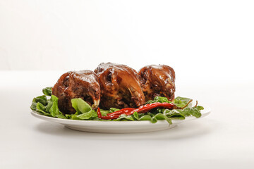 Traditional Braised Rabbit Heads with Spicy Glaze and Fresh Herbs on White Plate - Authentic Asian Cuisine Dish