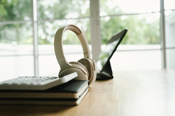 A modern home office with a laptop, headphones, notebook, and pen on a wooden desk, creating a clean and productive workspace atmosphere.