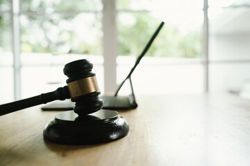 A judge's gavel placed on a wooden desk beside a laptop, symbolizing law, justice, court decisions,...