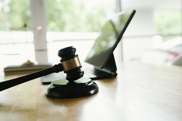 A judge's gavel placed on a wooden desk beside a laptop, symbolizing law, justice, court decisions,...