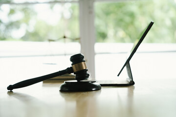 A judge's gavel placed on a wooden desk beside a laptop, symbolizing law, justice, court decisions, and legal proceedings in a modern office.
