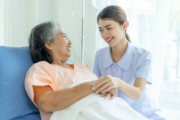 Fototapeta premium Smiling nurse taking care of elderly patient in hospital bed, healthcare support and medical service with compassion, professional caregiver providing assistance and encouragement to senior woman