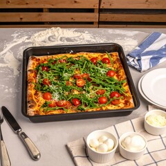 Square pizza in a dark pan on a gray table