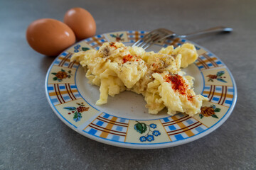 scrambled eggs with seasoning on plate and whole eggs nearby