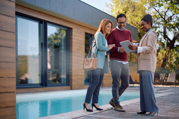 Fototapeta premium Happy black real estate agent using touchpad with couple during real estate showing.