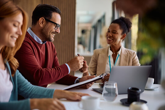 Happy man signing a contract during a meeting with insurance agent. - Powered by Adobe