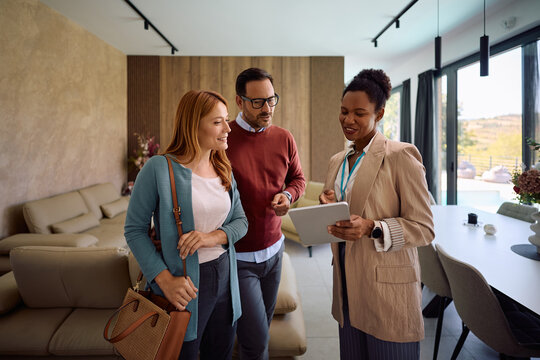 Black real estate agent and her clients using digital tablet during open house day.