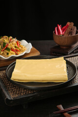 Fresh Handmade Tofu Skin Sheets on Dark Plate with Traditional Asian Cooking Ingredients