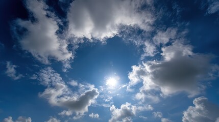 Obraz premium Azure sky is filled with puffy, brilliant white clouds surrounding the bright sun