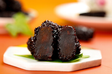 Large Black Dried Jujubes from Shaanxi Province China on White Plate with Green Leaves