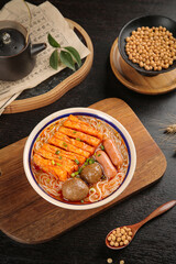 Asian noodle soup with tofu and sausage served on wooden board with soybean ingredients studio shot