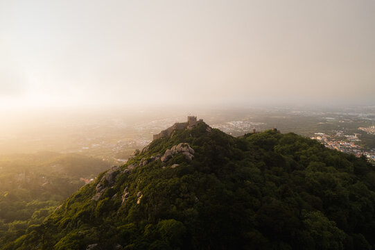 Castle of the Moors in epic golden light through fog, in Portugal Sintra