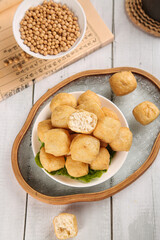Handfried tofu bean puffs dish with soybeans in rustic wooden bowl casserole style Asian vegetarian food photography