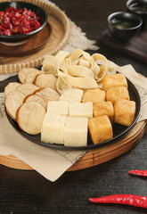 Assorted tofu varieties on cast iron pan for Asian hot pot cooking with traditional ingredients
