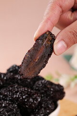 Hand Holding Large Dried Black Jujube Fruit Close-Up