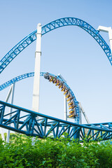 Roller coaster Ride against blue sky. Roller coaster in the amusement park. Cheerful entertainments in park of attractions