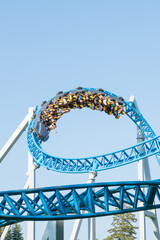 Roller coaster Ride against blue sky. Roller coaster in the amusement park. Cheerful entertainments in park of attractions