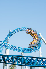 Roller coaster Ride against blue sky. Roller coaster in the amusement park. Cheerful entertainments in park of attractions