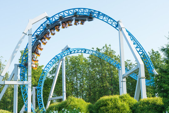 Roller coaster Ride against blue sky. Roller coaster in the amusement park. Cheerful entertainments in park of attractions