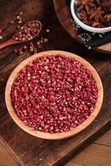 Red Sichuan Hanyuan Pepper Granules in Wooden Bowl with Star Anise on Rustic Wood Background
