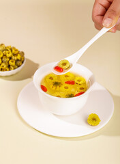 Traditional chrysanthemum flower tea with goji berries in white cup - herbal health drink concept