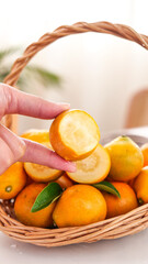 Hand holding sliced kumquat from basket of fresh citrus fruits with smooth crispy skin