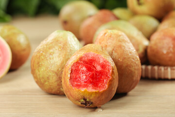 Fresh Red Guava Fruits from Guangxi China with Soft Pink Heart-Shaped Flesh on Wood Background