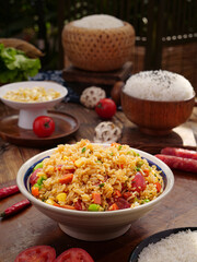 Delicate rice casserole with salami and mixed vegetables served in traditional ceramic bowl on wooden table