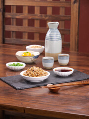 Japanese Natto Fermented Soybeans with Sake and Traditional Small Dishes on Wooden Table