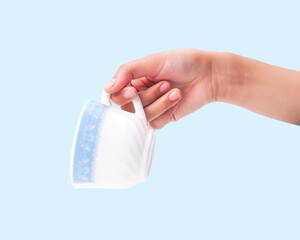 Female hand holding elegant white and blue patterned cup on light blue