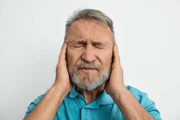Fototapeta premium Elderly man feels discomfort in his ear, illustrating the challenges of hearing loss and ear problems he faces daily