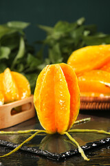 Fresh Star Fruit Slices on Dark Wood Background with Tropical Foliage