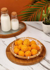 Golden Sesame Fried Dumplings in Bamboo Steamer with Milk Bottles and Palm Leaves on Marble Table