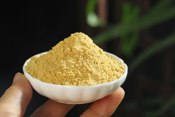 Natural ginger powder spice in bowl - healthy yellow seasoning for cooking and wellness