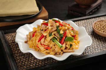 Handmade Tofu Skin Noodle Stir Fry with Vegetables on Traditional Woven Placemat - Asian Cuisine