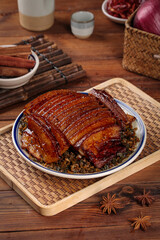 Traditional Chinese braised pork belly with plum sauce dried vegetables and chopsticks on wooden bamboo serving tray