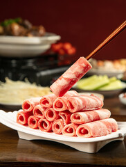 Raw lamb meat rolls with chopsticks for hot pot shabu shabu Asian cooking ingredients on white plate © ChauKhanh