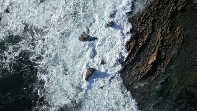 Calm 4K drone shot hovering over gentle waves hitting rocks at Laguna Beach shoreline. Slow motion capable, perfect for ocean, nature, travel, or cinematic projects.