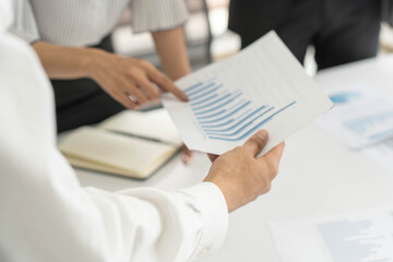 Financial consultant team analyzing company marketing plan. Businessman pointing to document on the table in meeting.