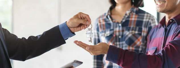 Obraz na płótnie Canvas close up view hand of property realtor landlord giving key house to buyer tenant. banner wide side.