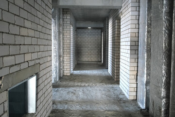 Rough finishing flat with cement floor in room during construction of building. Rough repairs for self-finishing. Cement interior decoration, bare brick block walls of room, stage of construction.