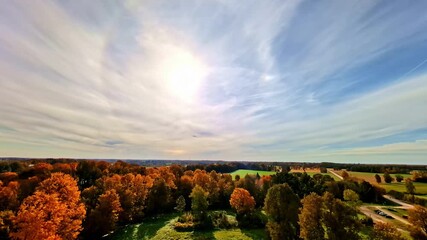 A circular halo surrounds the sun above a colorful autumn forest and open countryside. Europe - Powered by Adobe