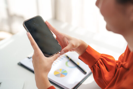 Businesswoman using smartphone with blank screen in office setting