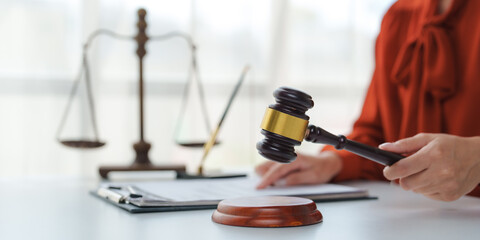 Judge holding gavel in courtroom with scales of justice